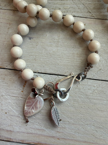 Tibetan carved bone dahlia pendant on hand knotted riverstone beads necklace. Fine silver flower cluster and MOP leaf dangles.