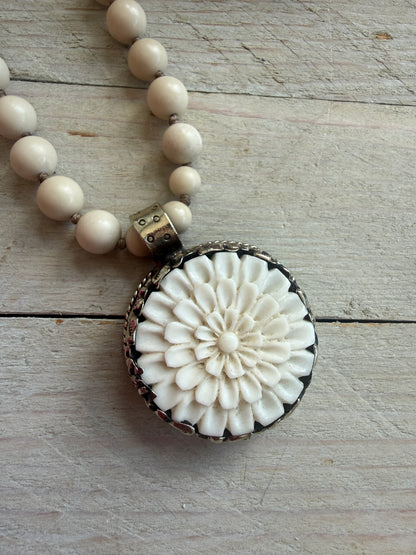 Tibetan carved bone dahlia pendant on hand knotted riverstone beads necklace. Fine silver flower cluster and MOP leaf dangles.