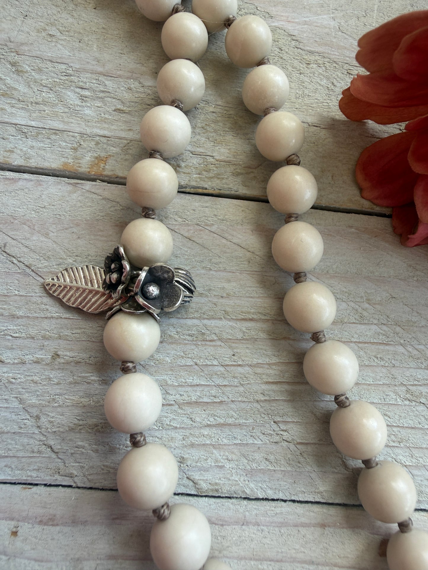 Tibetan carved bone dahlia pendant on hand knotted riverstone beads necklace. Fine silver flower cluster and MOP leaf dangles.