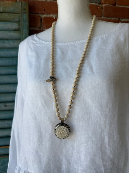 Tibetan carved bone dahlia pendant on hand knotted riverstone beads necklace. Fine silver flower cluster and MOP leaf dangles.