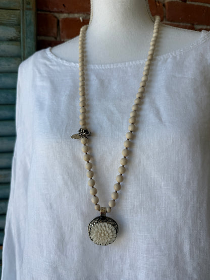 Tibetan carved bone dahlia pendant on hand knotted riverstone beads necklace. Fine silver flower cluster and MOP leaf dangles.