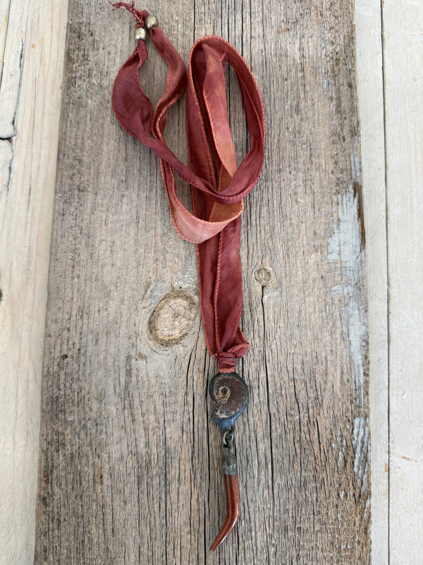 Ammonite and goldstone tusk on rust silk ribbon necklace. Adjustable to 36”
