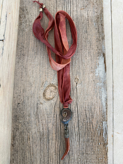 Ammonite and goldstone tusk on rust silk ribbon necklace. Adjustable to 36”