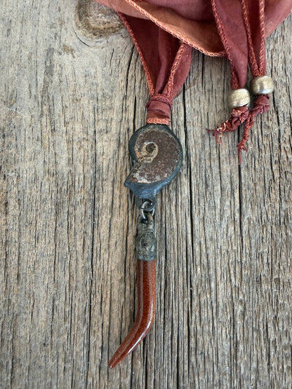 Ammonite and goldstone tusk on rust silk ribbon necklace. Adjustable to 36”