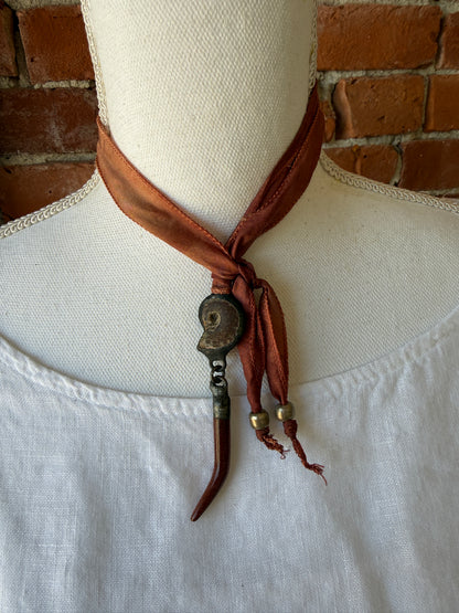 Ammonite and goldstone tusk on rust silk ribbon necklace. Adjustable to 36”