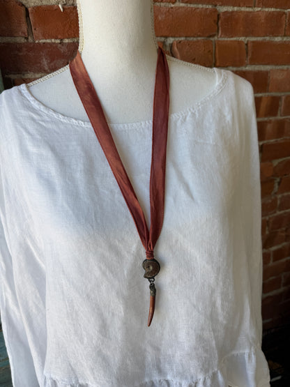 Ammonite and goldstone tusk on rust silk ribbon necklace. Adjustable to 36”