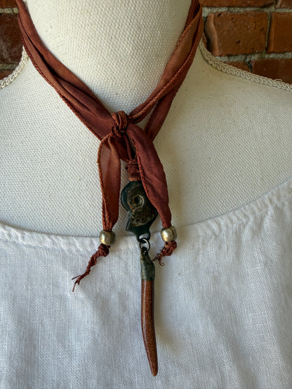 Ammonite and goldstone tusk on rust silk ribbon necklace. Adjustable to 36”