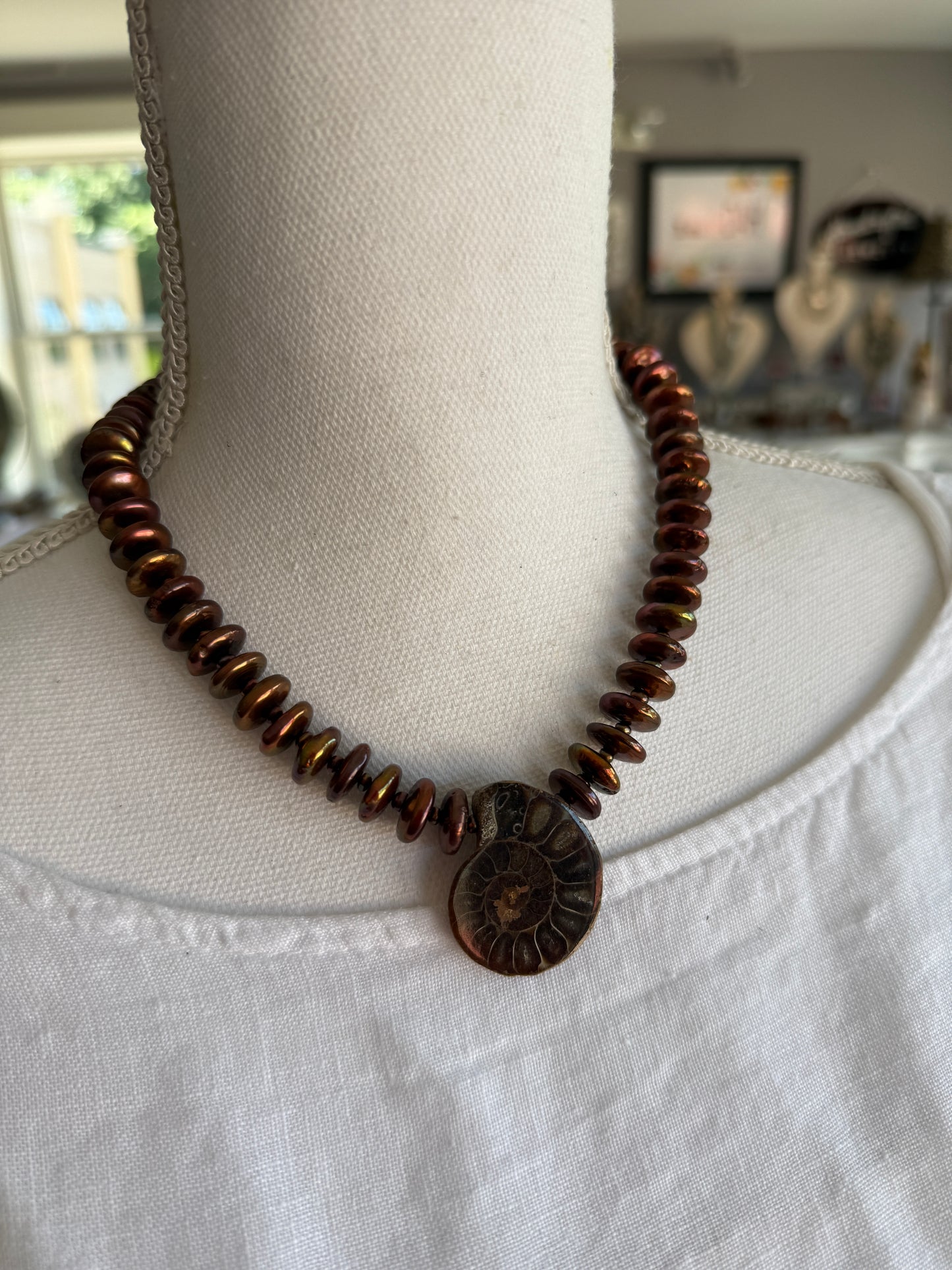 A natural ammonite fossil and chocolate brown button pearl necklace.