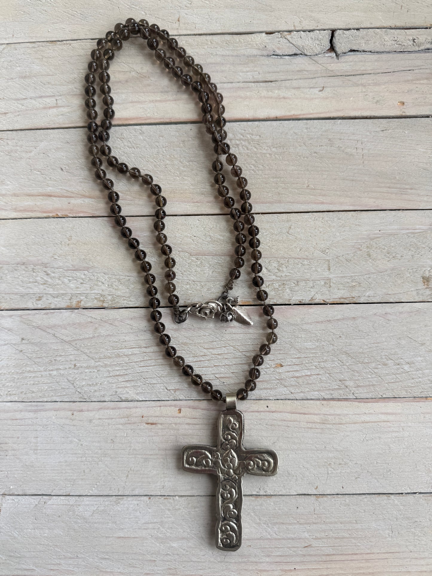 Blue kyanite cross on knotted smoky quartz necklace with fine silver flower accents.