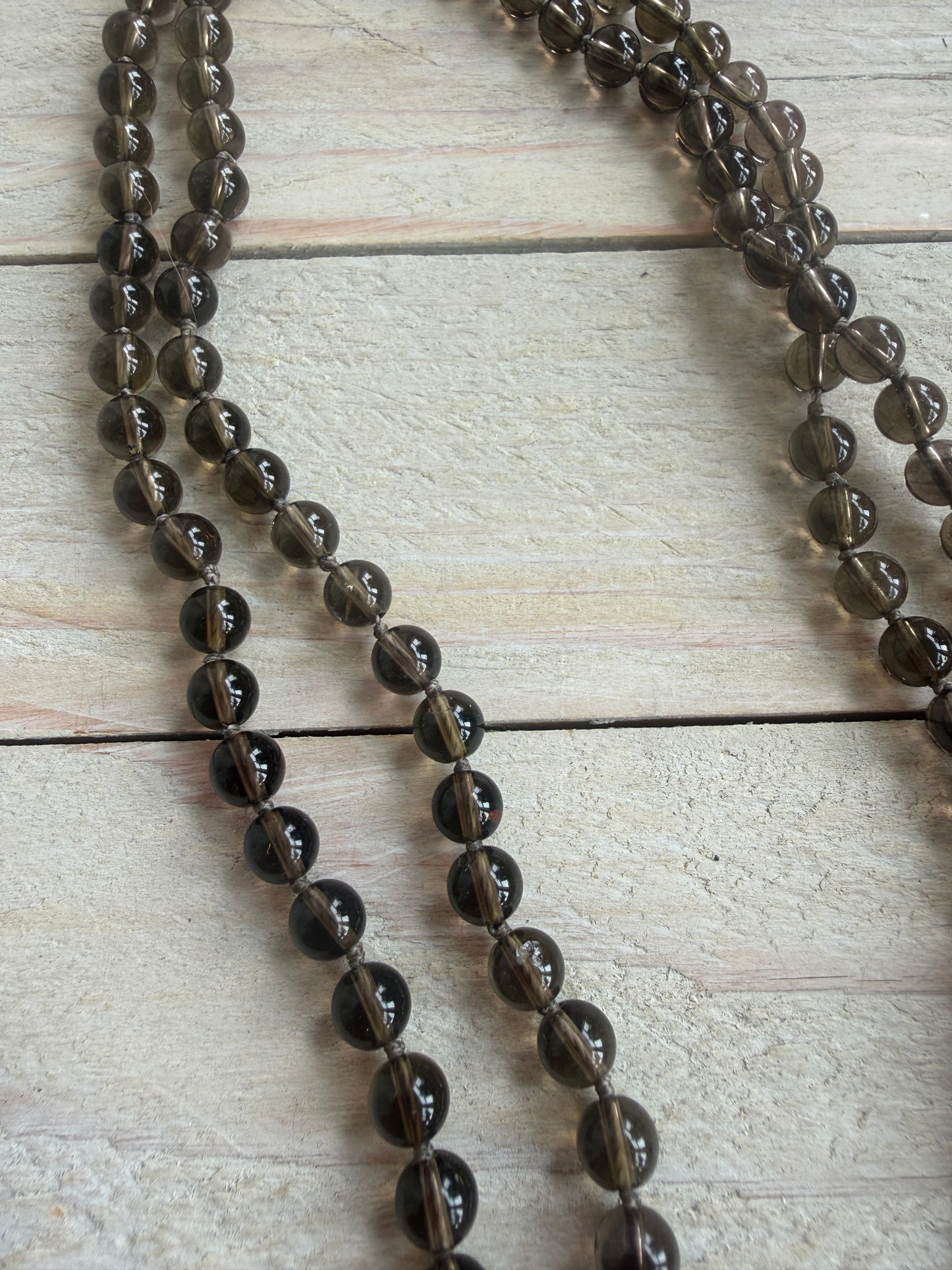Blue kyanite cross on knotted smoky quartz necklace with fine silver flower accents.