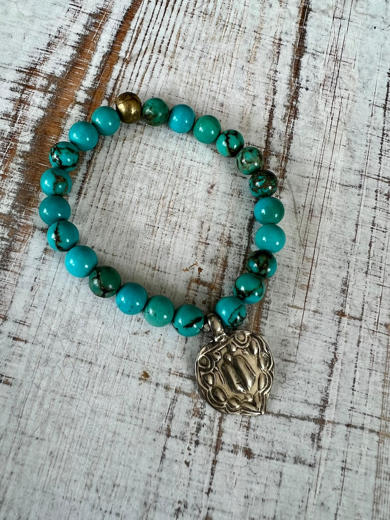 Lotus feet. Artisan made charm suspended on turquoise rounds stretch boho yogi bracelet. 7”