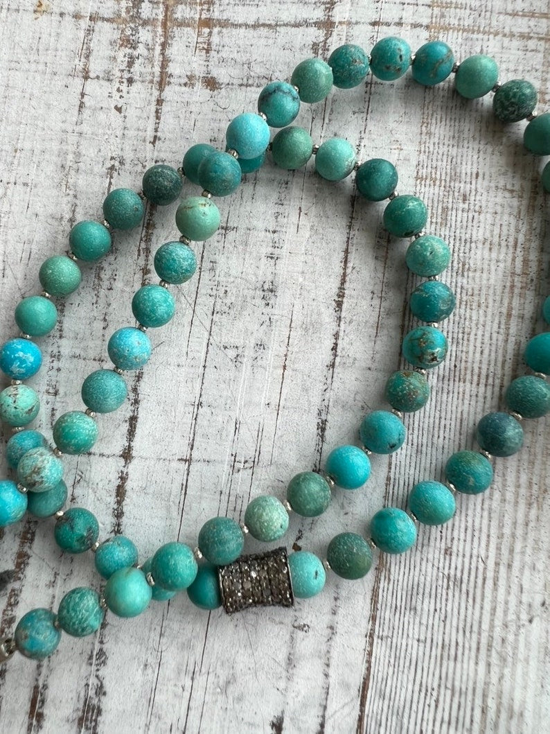 Matte turquoise beads with a pavé diamond barrel bead focal. Adjustable necklace with grey deerskin and fine silver accents. OOAK.