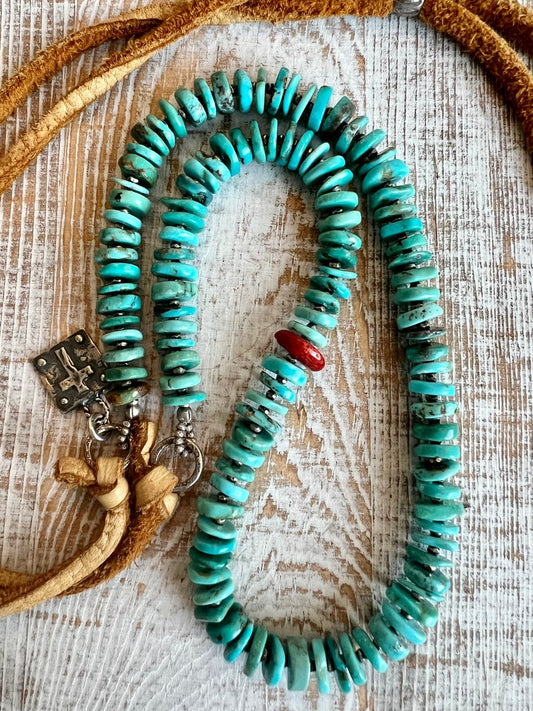 Turquoise heishi beads with fine silver spacers and one coral bead on adjustable deerskin