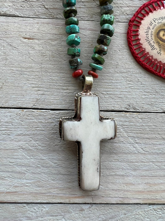 Tibetan bone cross on turquoise heishi beads. Adjustable deerskin leather.