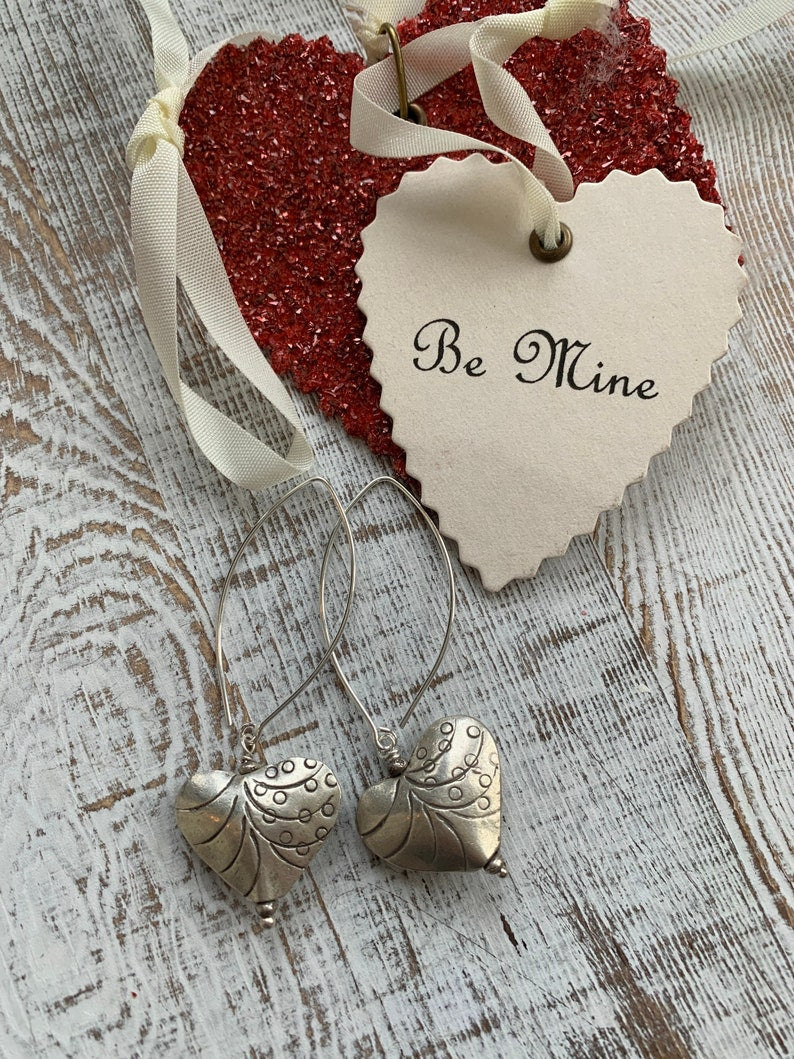 Fine silver stamped heart earrings on ellipse-shaped sterling ear wire. Sister, wife, daughter, gf gift