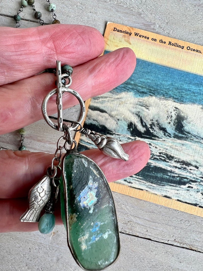 Ancient Roman glass with a beach vibe on tiny faceted turquoise chain. Fine silver shell, fish and stamped toggle.